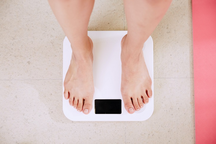 person weighing self on scales