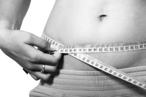 person measuring belly fat